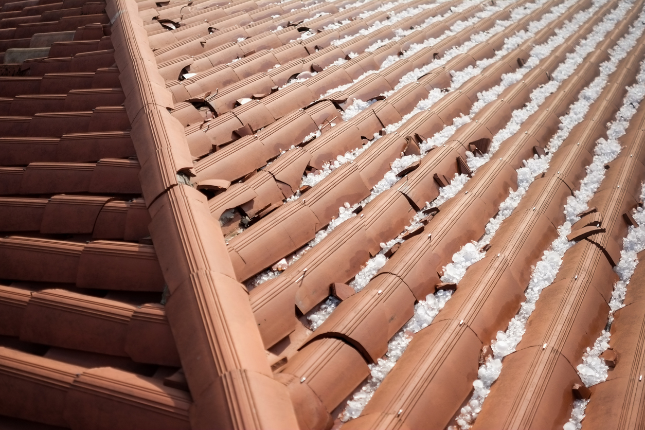 A damaged brown residential roof because of hail storm.